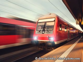 538597602-Wunderschöne Bahnhof mit modernen roten Pendlerzug während dem Sonnenuntergang